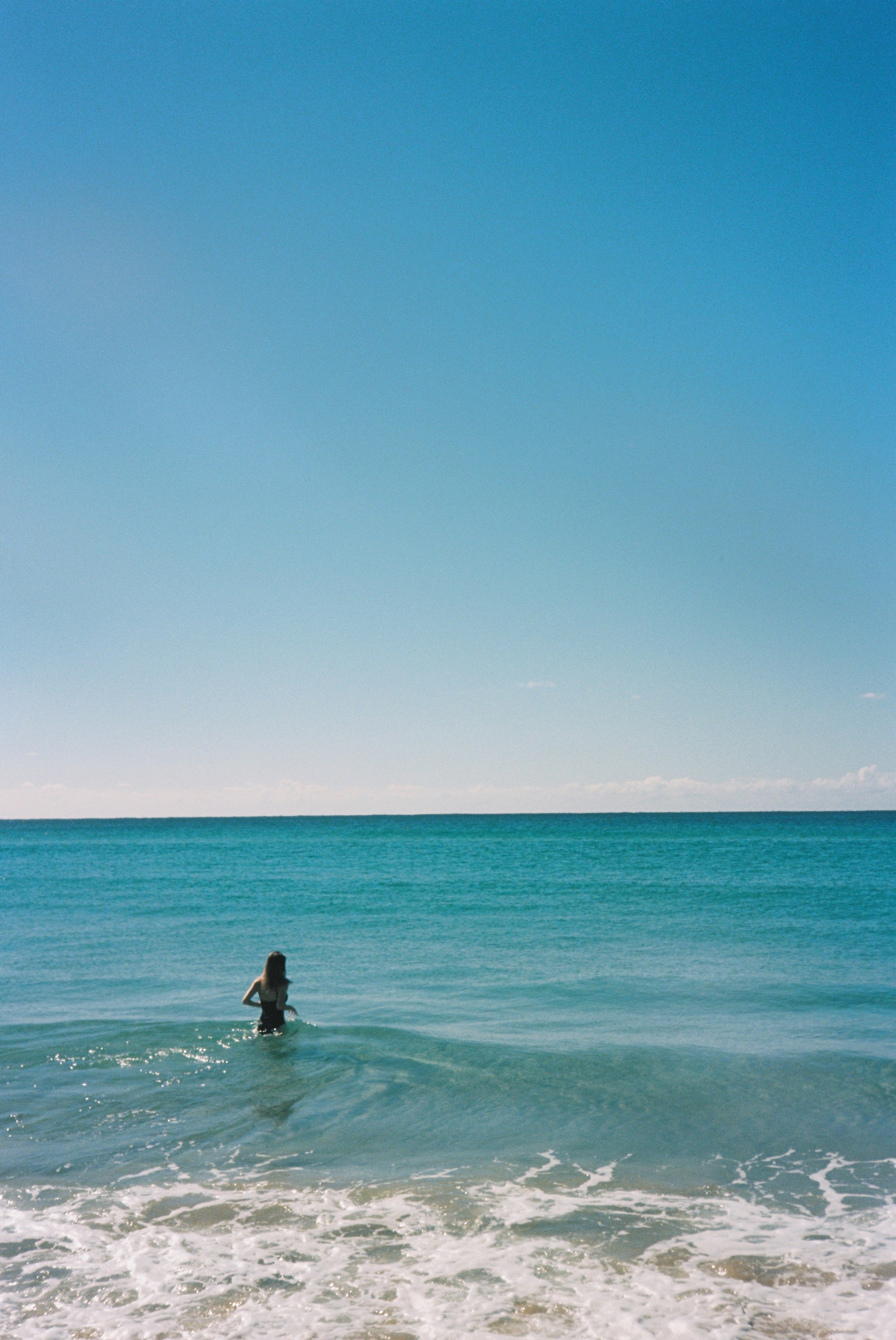 Person swimming with clear blue sky and water.
